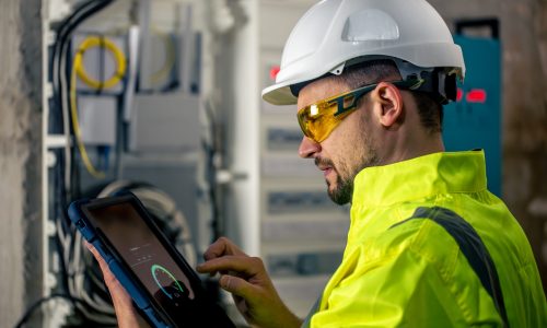 Man, an electrical technician working in a switchboard with fuses. Installation and connection of electrical equipment.