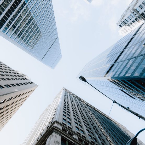 A vertical low angle shot of the skyscrapers under the bright sky in New York City, United States